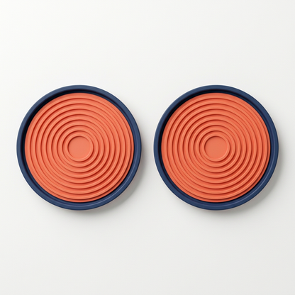 Two matching navy coral round coasters isolated side by side on white